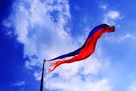 菲律宾国旗在明亮的蓝天下飘扬，象征着爱国主义与自由