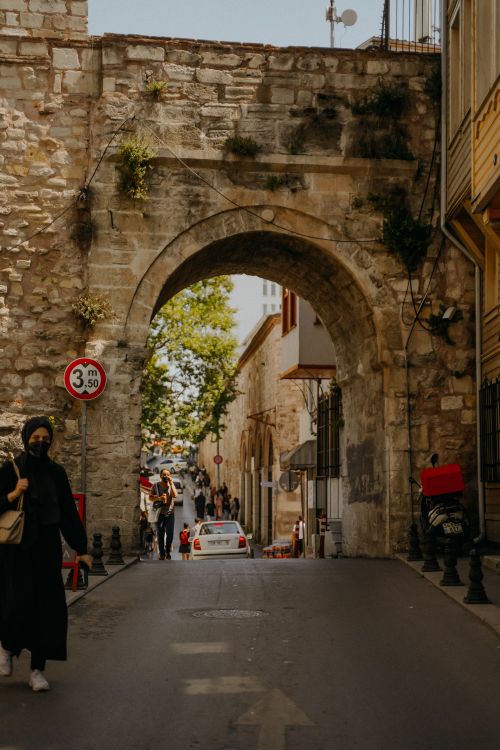 Free People walking on narrow asphalt road near aged stone archon street in town on sunny summer day Stock Photo