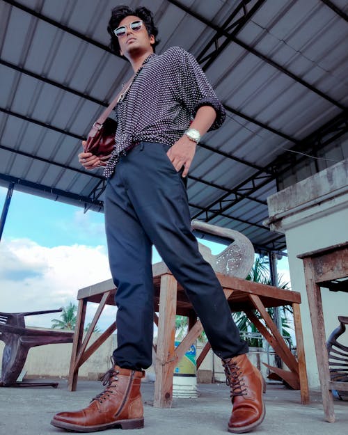 Photo of a Man Wearing Brown Leather Boots Posing with His Hand in His Pocket