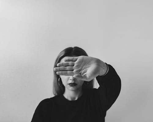 Free Grayscale Photo of a Woman Covering Her Face from the Camera Stock Photo