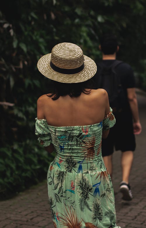 Woman Wearing a Green Dress and a Hat Walking the Street