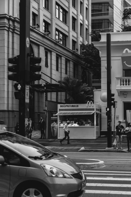 Black and white photo of a busy street in São Paulo, showing pedestrians and traffic.