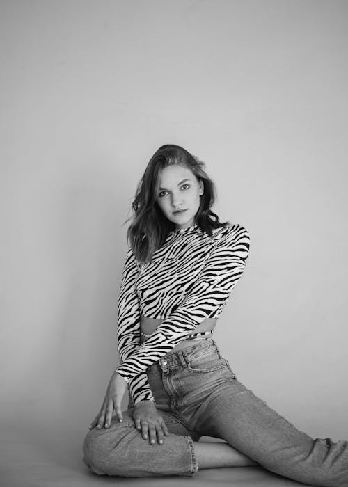 Free A Grayscale of a Woman Wearing an Animal Print Top and Denim Pants Stock Photo