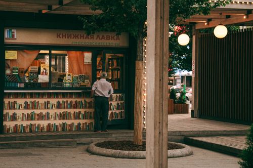 Free Man stands at an outdoor bookstore in Moscow, surrounded by hanging lights and books on display. Stock Photo