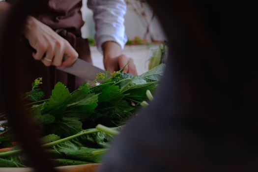 Close-up of a person cutting fresh leafy greens on a kitchen counter, showcasing healthy cooking.