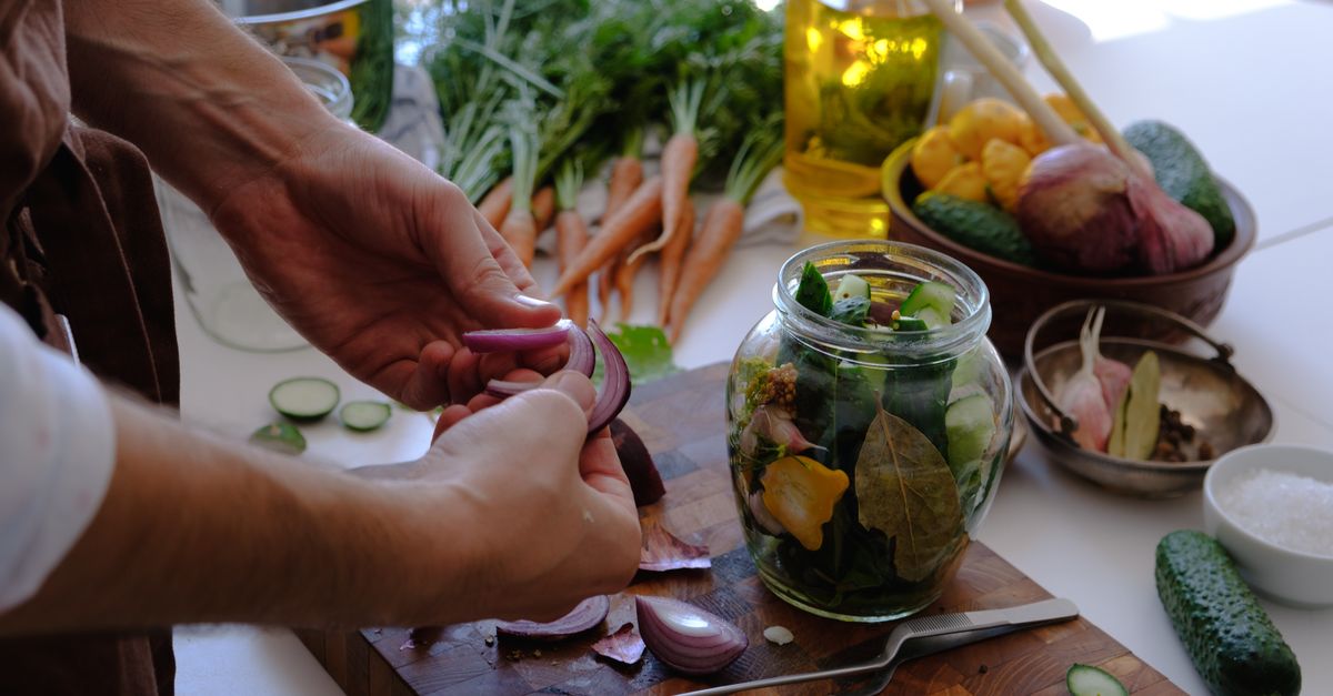 Home cook proudly holding a jar of homemade pickled vegetable scraps