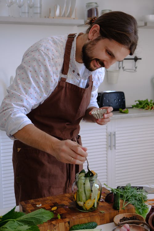 Free A Bearded Man in Brown Apron Preparing Food on a Glass Jar Stock Photo