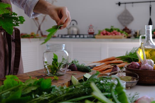 Hand preparing herbs and vegetables in a kitchen setting. Fresh ingredients on a rustic table.