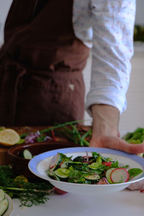 Free A hand serving a fresh, healthy vegetable salad on a white plate indoors. Stock Photo