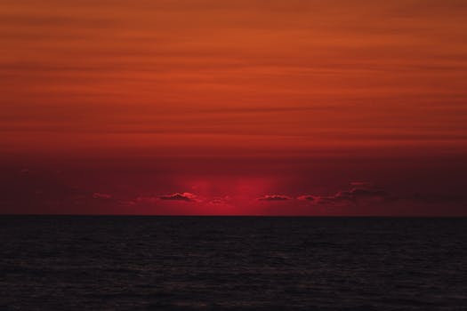Capture of the serene ocean at sunset with a vivid red sky, perfect for nature and travel visuals.