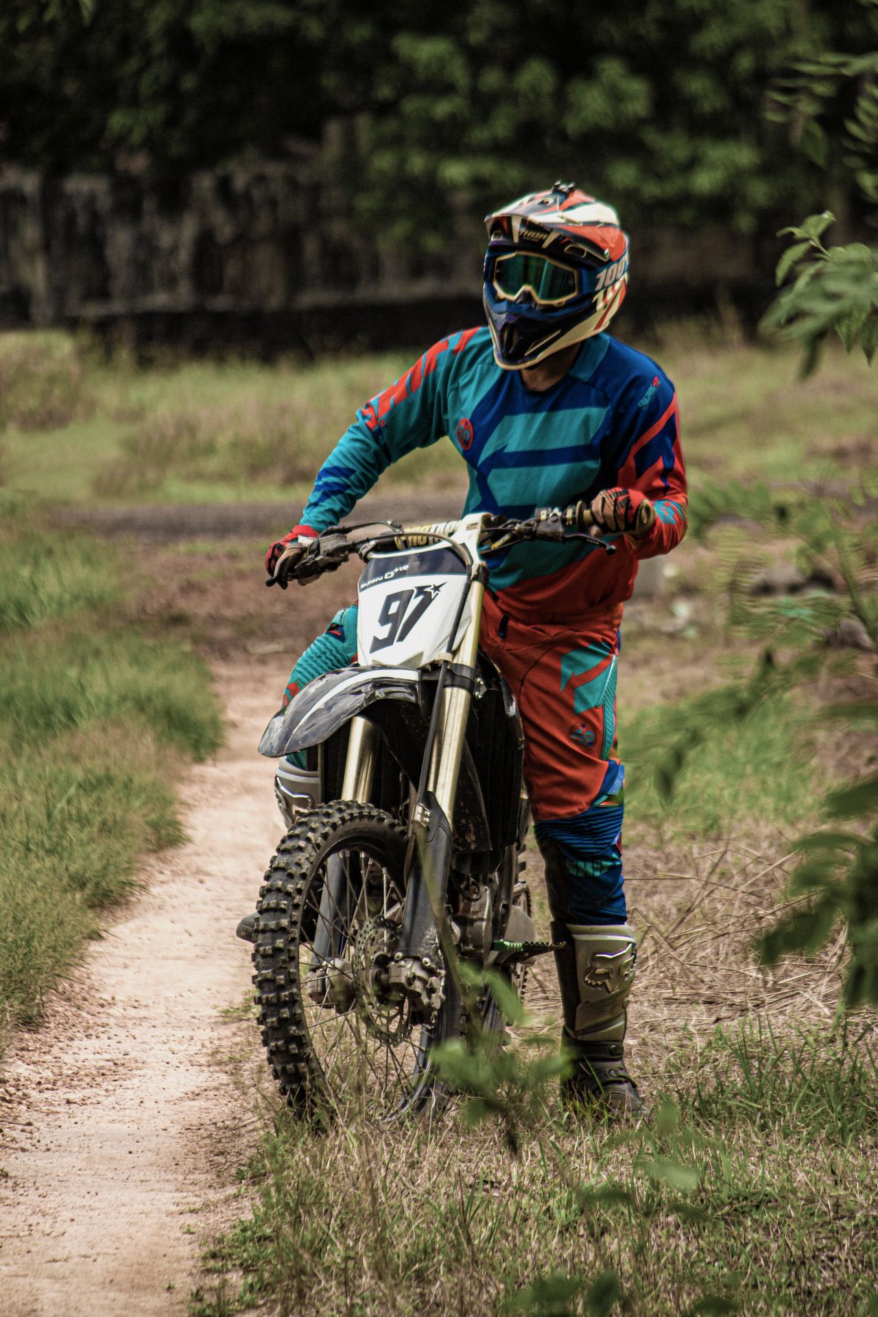 A dirt bike rider on a narrow trail