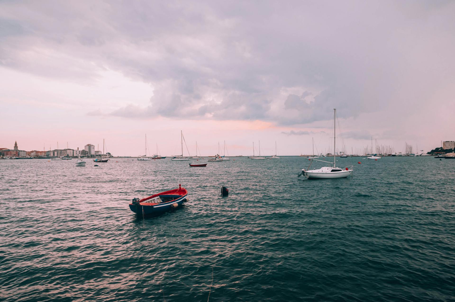 A tranquil seascape featuring sailboats on the Croatian coastline under a cloudy sky.