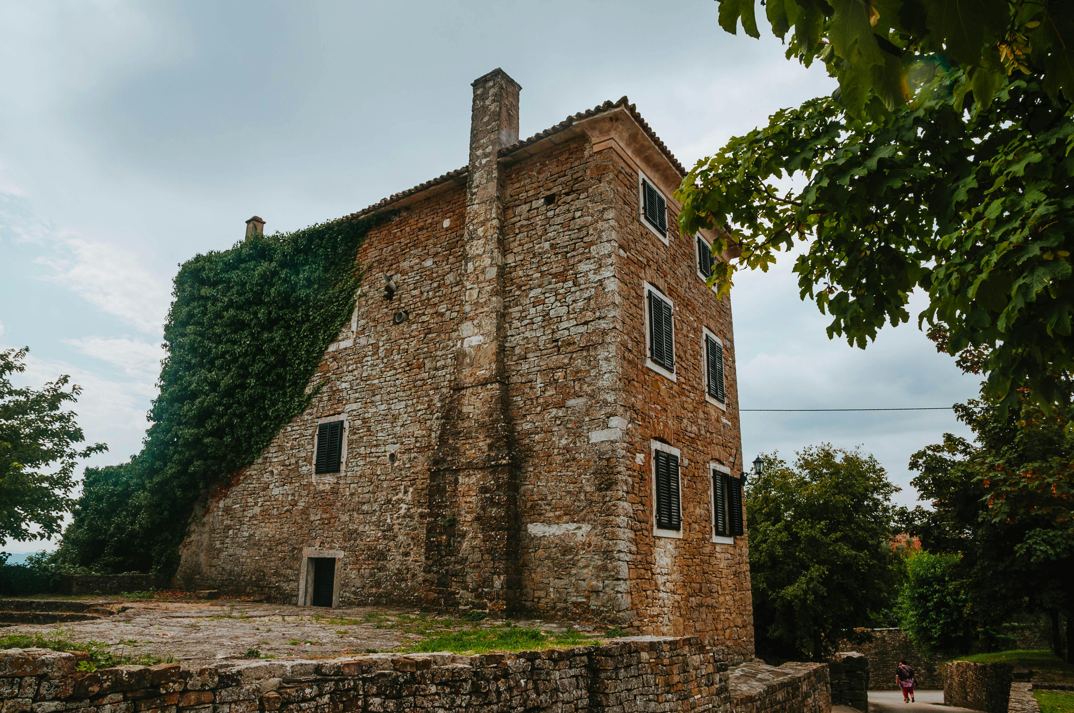 Free A scenic view of a historic brick house covered in ivy, surrounded by lush trees. Stock Photo
