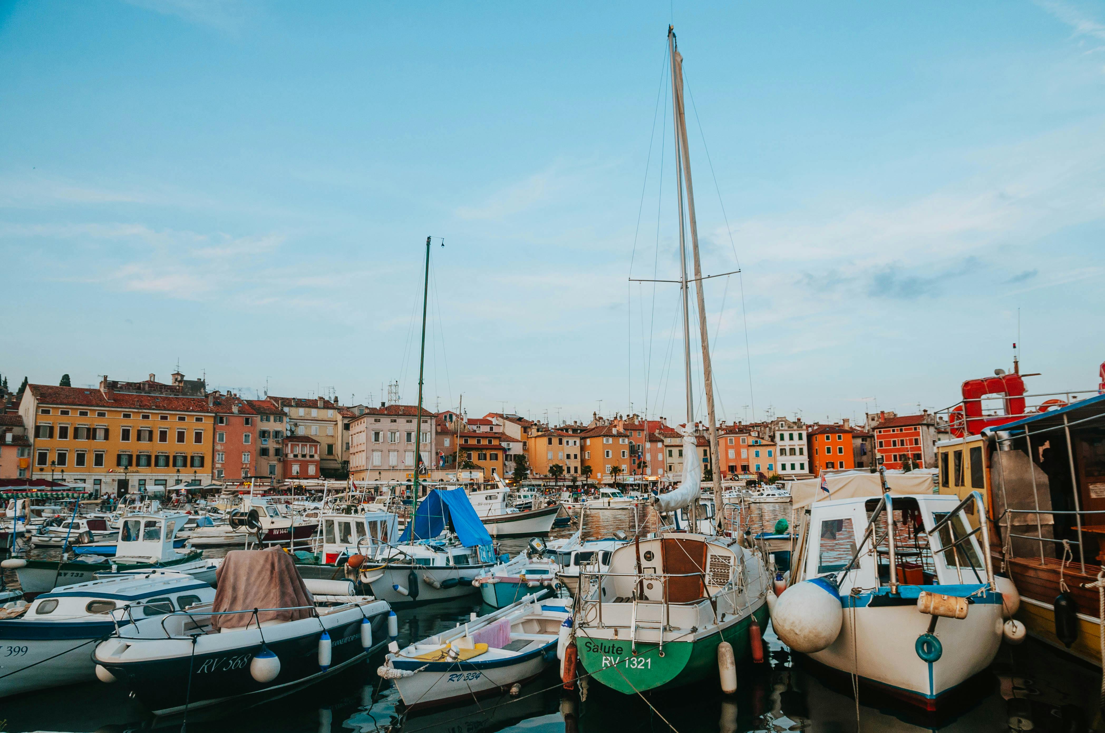 Vibrant marina with docked boats against colorful coastal town backdrop in Croatia. - Rovinj