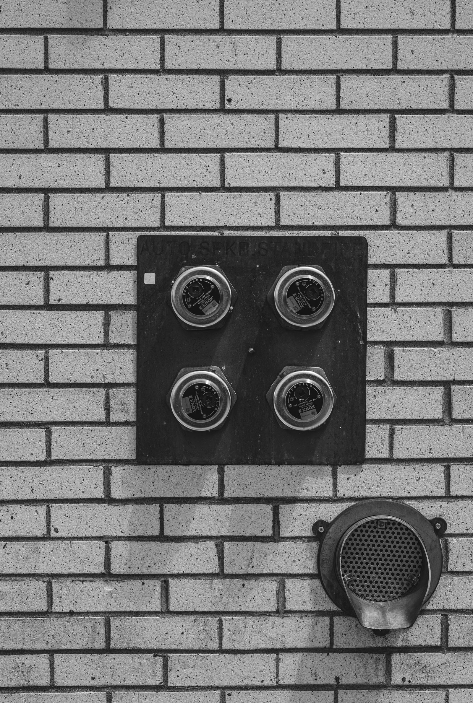 Medidor de energia instalado em uma parede, em fotografia em preto e branco.