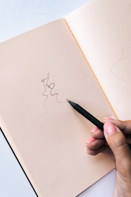 Free A Person Drawing on a Notebook Stock Photo