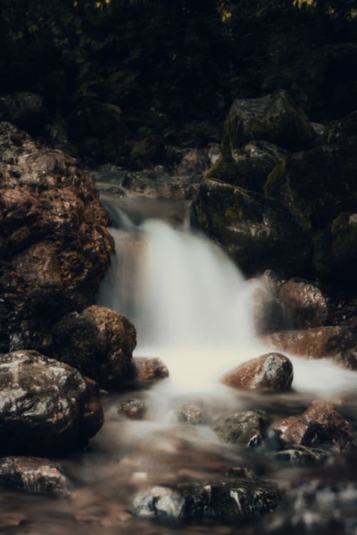 Free Calm water stream cascading over rocks in nature setting. Captured with long exposure. Stock Photo