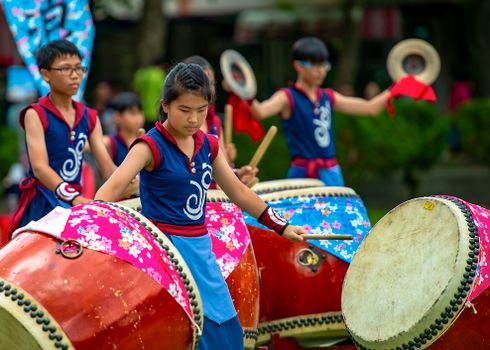 Young performers playing traditional Taiko drums in a vibrant outdoor Taiwanese parade.