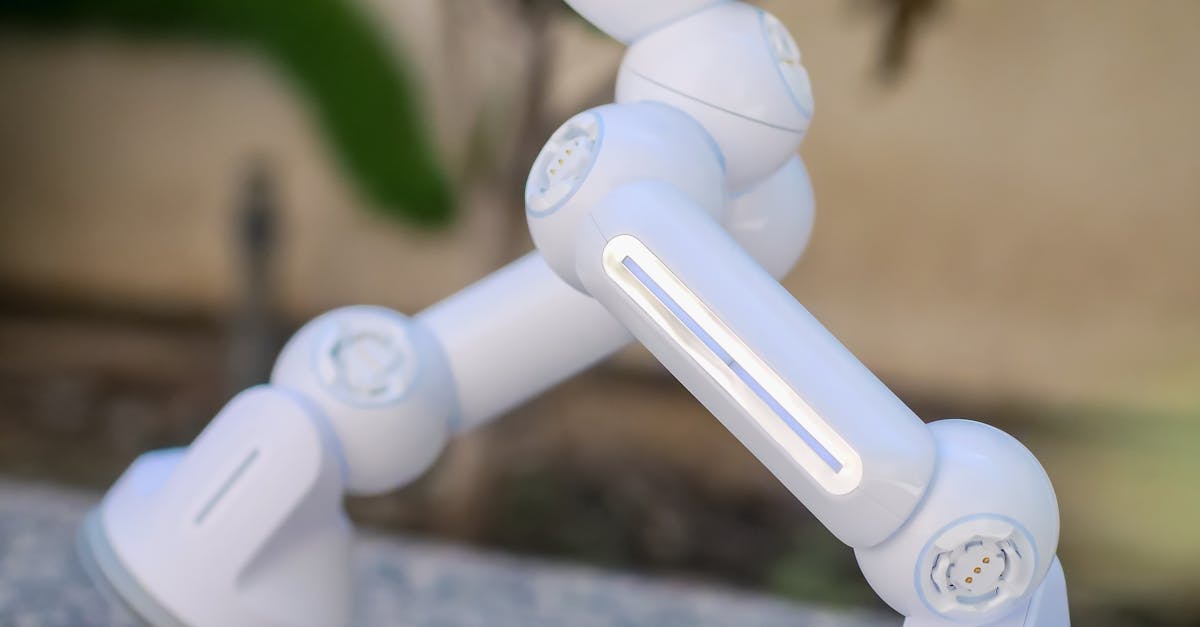 Close-up of a modern white robot with advanced design standing outdoors on pebbled ground.