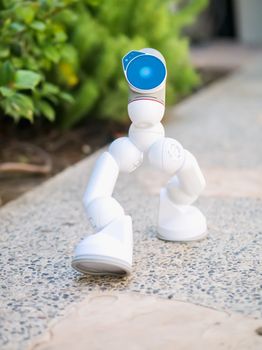 A close-up of a small, white robot showcasing advanced AI and technology outdoors.