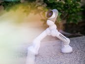 White Toy Robot on Gray Concrete Floor