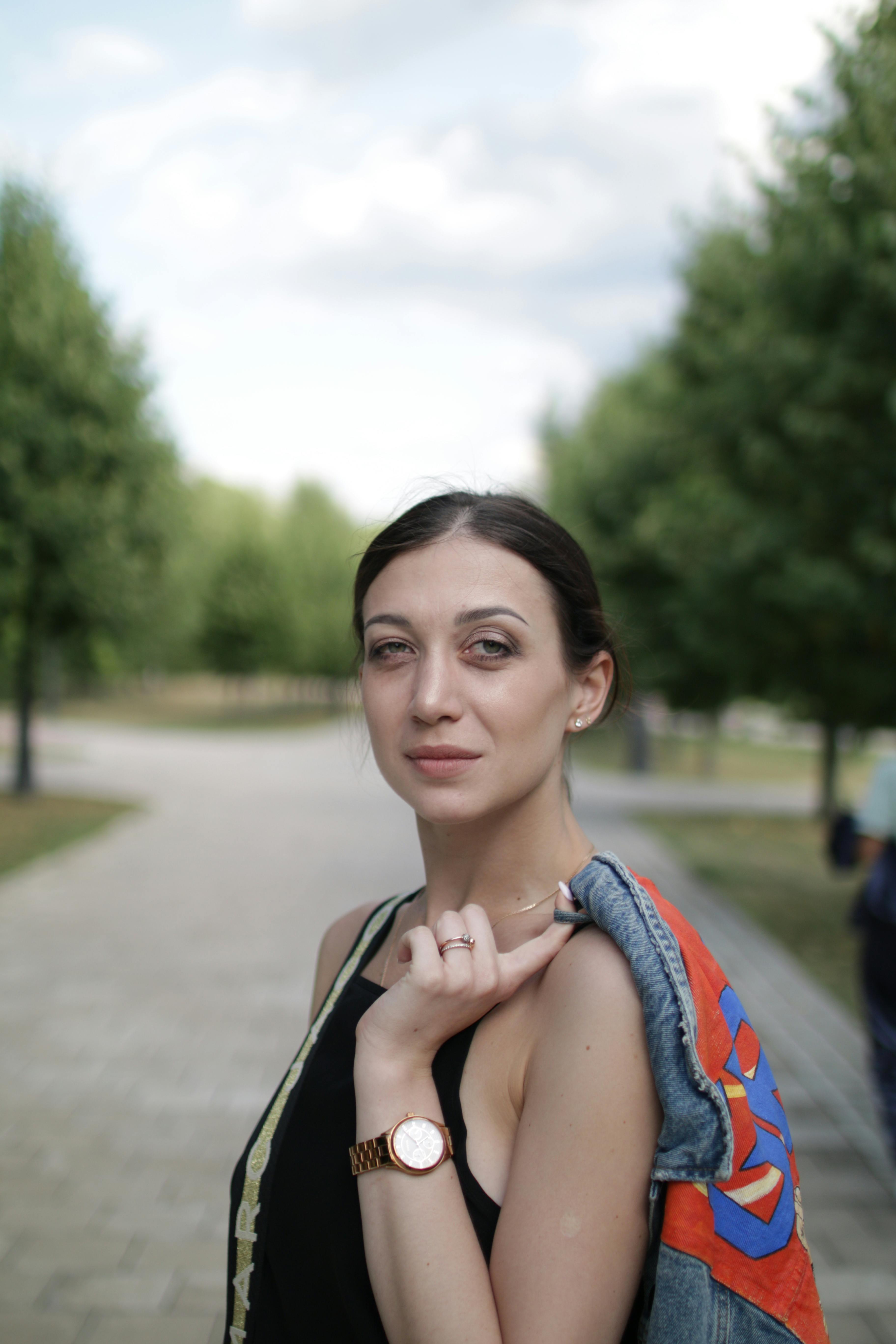 Confident woman posing outdoors with denim jacket and watch, showcasing casual style.