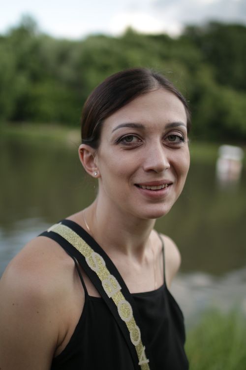 Free A smiling woman outdoors near a lake with a green forest background. Stock Photo