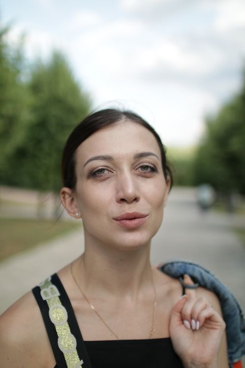 Free Close-up portrait of a woman outdoors with blurred green background. Stock Photo