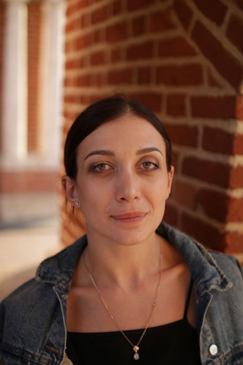 Free Woman in denim jacket posing against a red brick wall with natural light. Stock Photo