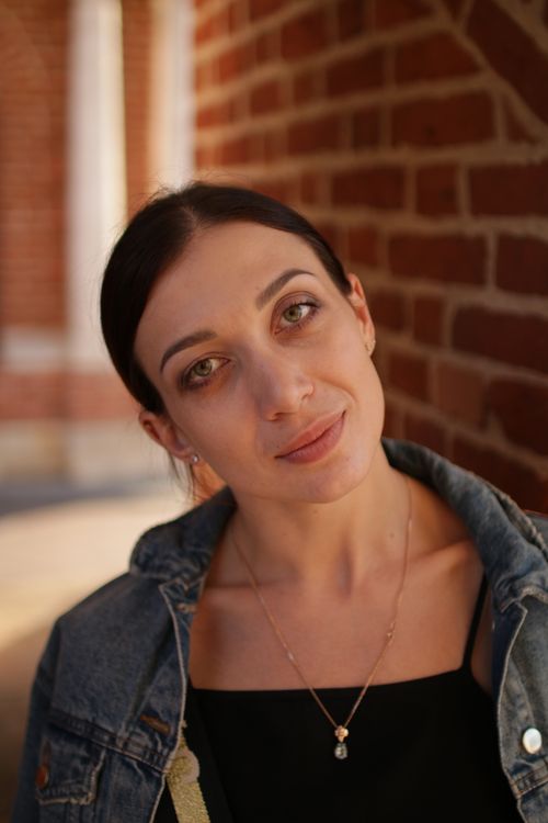 Free A woman wearing a denim jacket and necklace against a brick wall background. Stock Photo