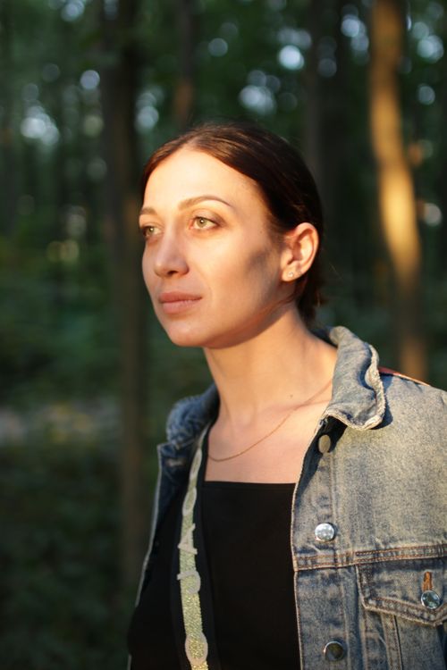 Free Portrait of a woman in a forest, wearing a denim jacket and illuminated by sunlight. Stock Photo