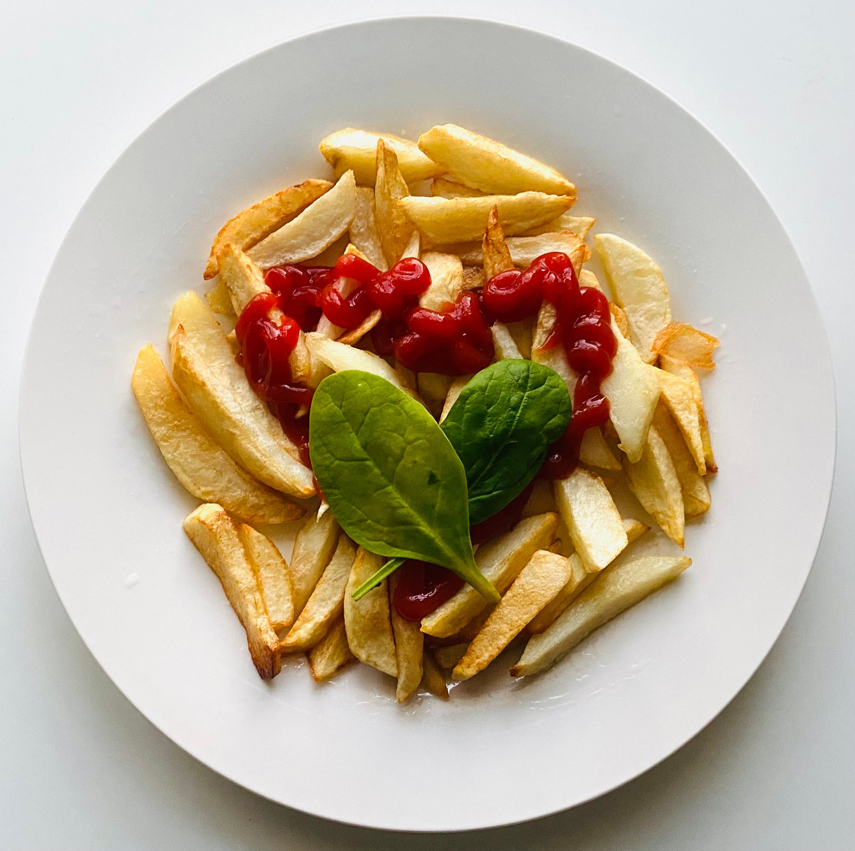 Ketchup bottle beside plate of french fries on table, representing France's school cafeteria condiment rules