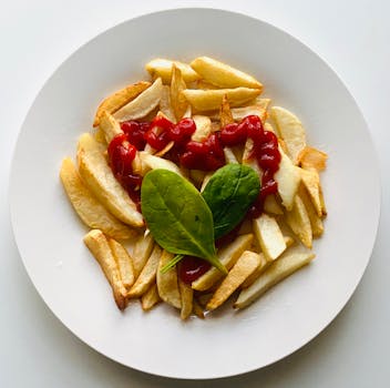 Delicious crispy french fries served with ketchup and spinach leaf garnish.