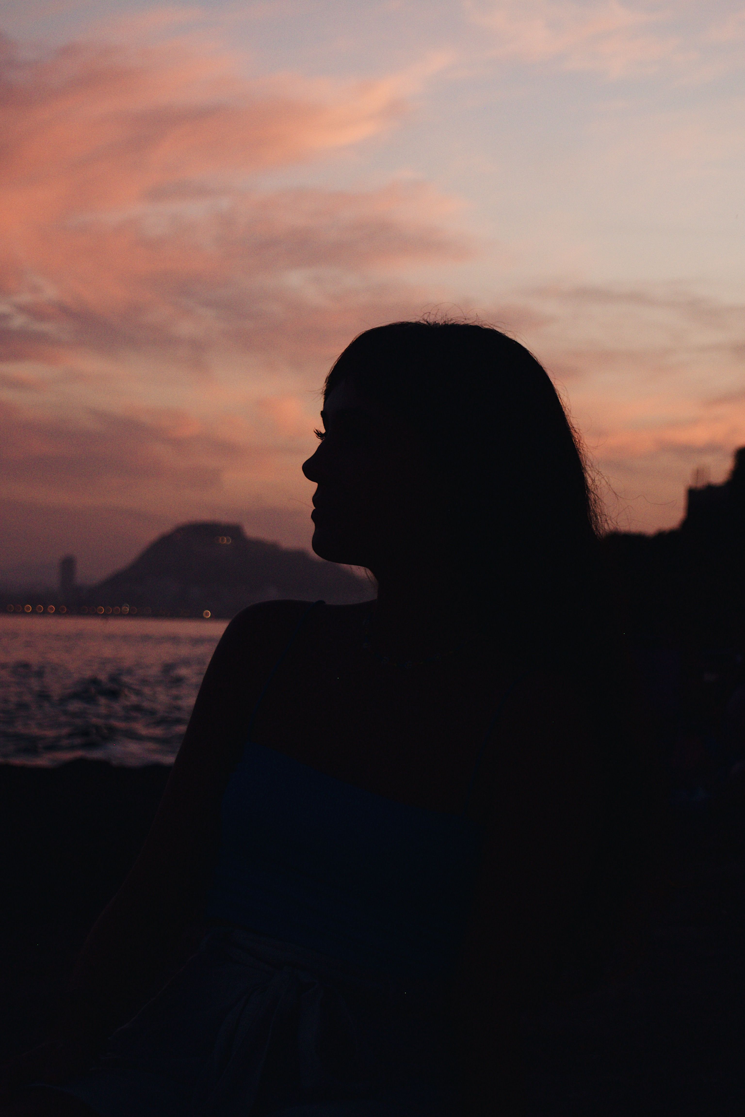 Silhouette of Woman Standing Near Water During Sunset · Free Stock Photo