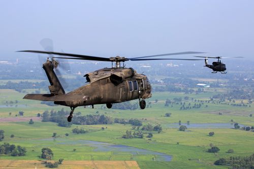 Free Aerial view of military helicopters flying over a green landscape on a clear day. Stock Photo