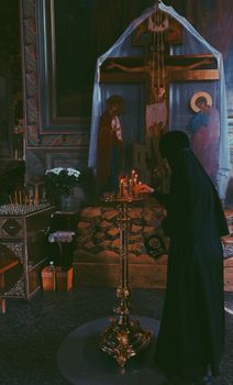 A nun lighting candles in a church, capturing a spiritual moment in Vladimir, Russia.