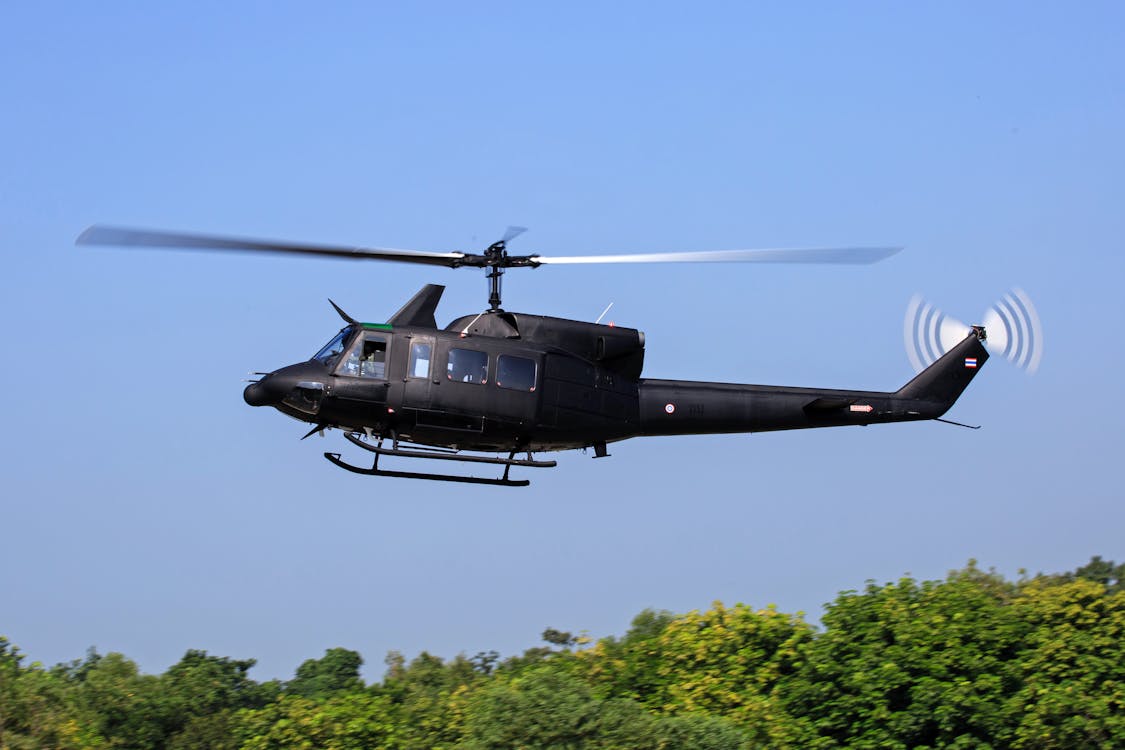 無料 緑の木々の上を飛んでいる黒いヘリコプター 写真素材
