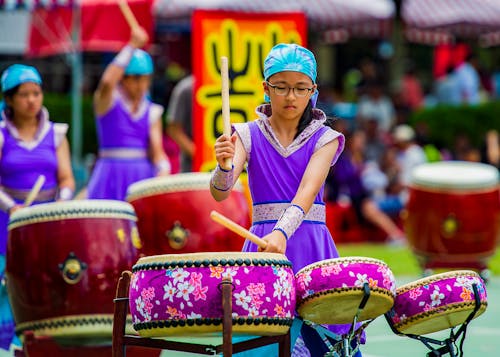 Girl in Purple Dress Playing Drums