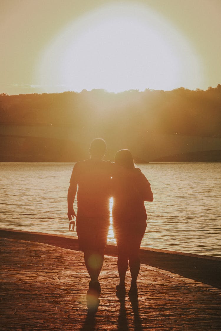 Silhouette Of A Couple Walking Together On The Beach