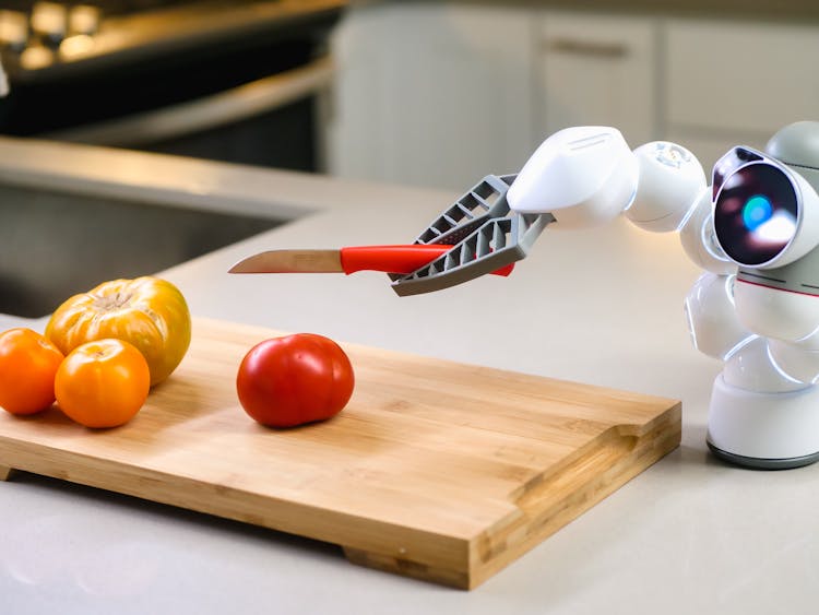 A Clicbot Slicing Holding A Knife Near Wooden Chopping Board