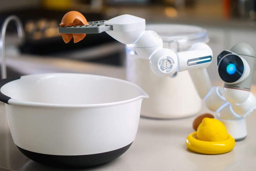 A robotic helper cracks an egg into a bowl in a contemporary kitchen setting, showcasing automation in cooking.