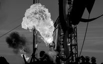 Grayscale Photo of Shirtless Man Blowing Fire