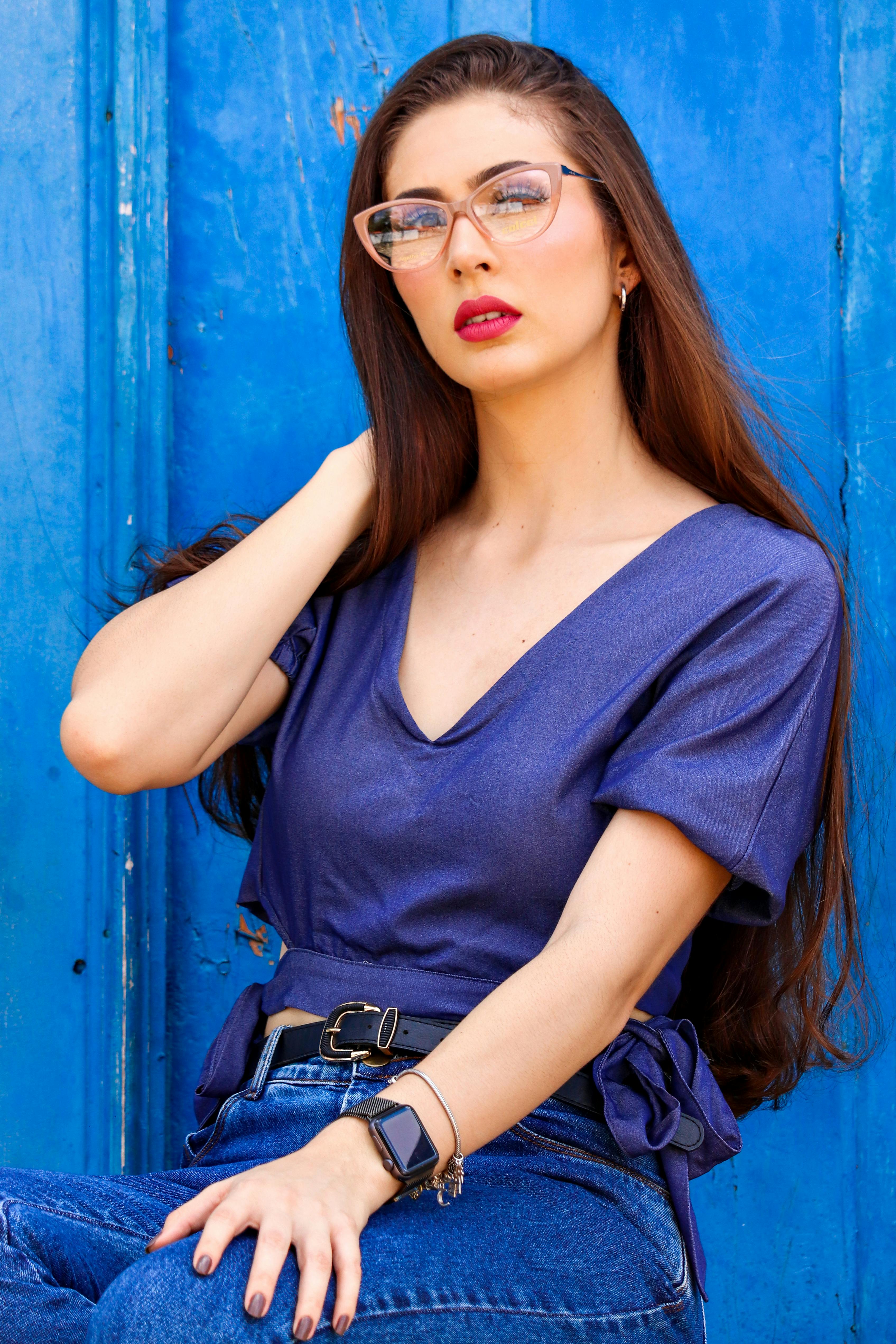 Portrait of a fashionable woman in eyeglasses posing against a vibrant blue backdrop. Ideal for lifestyle and fashion concepts.