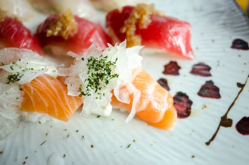 Free Artistic close-up of gourmet sushi featuring fresh salmon and tuna with garnishes, showcasing vibrant colors and textures. Stock Photo