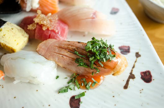 A close-up view of an artfully plated assortment of sushi garnished with herbs.