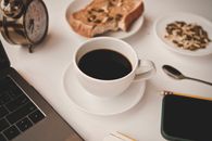 A Cup of Black Coffee Near Gadgets on a White Surface