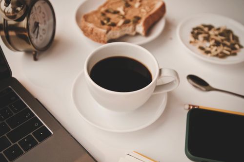 Free A high-angle view of a coffee cup, toast, and tech devices on a white surface, evoking a cozy morning vibe. Stock Photo