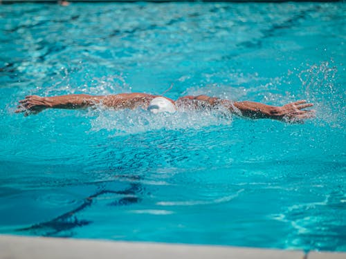 A Person Wearing a White Swim Cap Swimming in the Pool