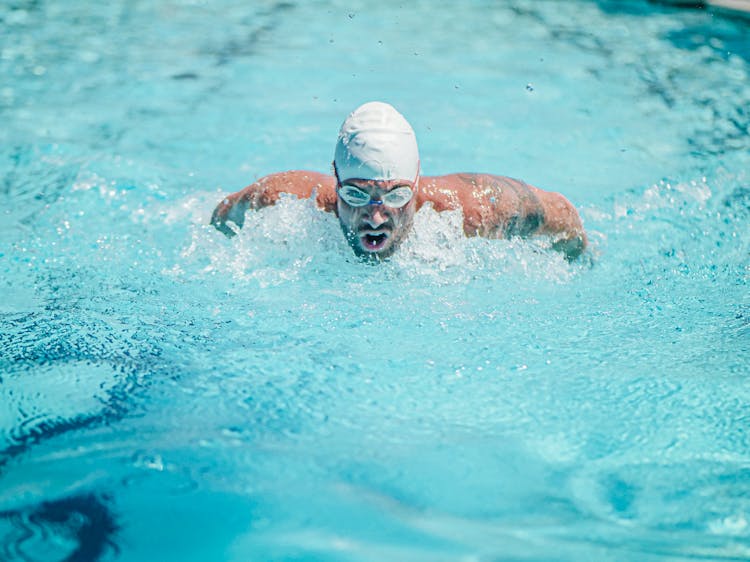 A Man In Swimming Cap And Goggles Swimming On The Pool