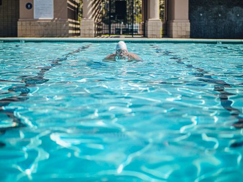 Free A swimmer practicing in an outdoor pool wearing goggles and a swim cap. Stock Photo